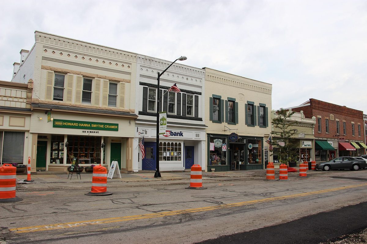 Two- and three-story storefronts in the Hudson Historic District, with orange construction barrels lined up along the street in front