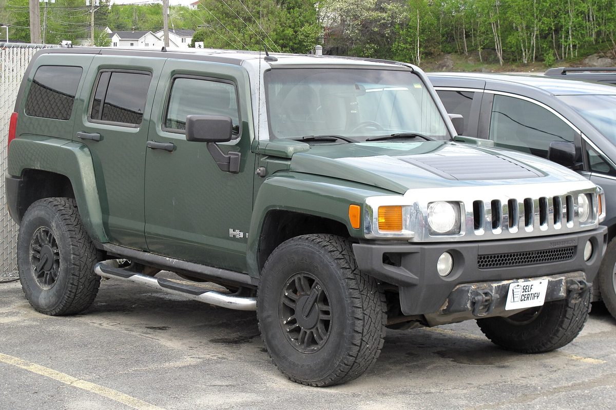 A dark green 2006 Hummer H3 SUV with black wheels, off-road tires and chrome side steps, parked in a lot