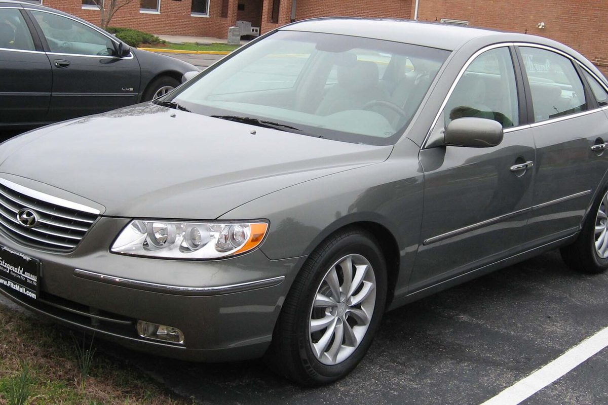 A gray 2007 Hyundai Azera sedan parked in a lot in front of a brick building