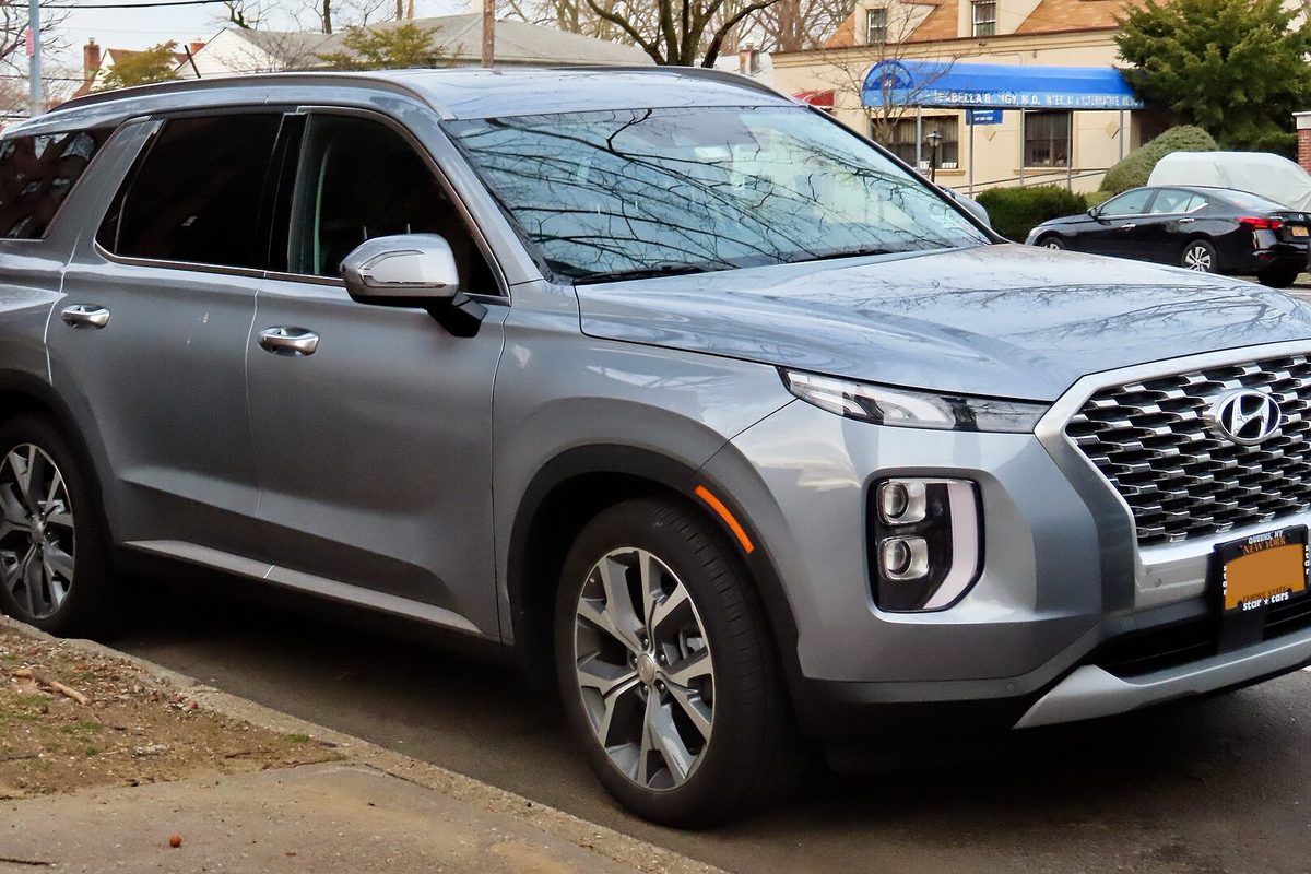 A silver 2020 Hyundai Palisade three-row SUV with a large chrome grille, parked at a residential curb