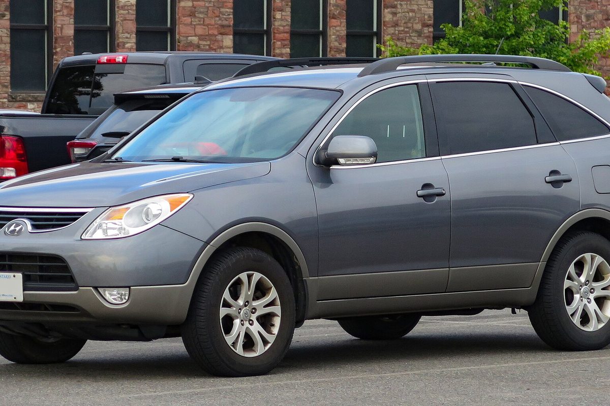 A gray Hyundai Veracruz SUV parked in a lot in front of a brick building