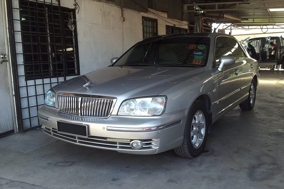 A silver Hyundai Grandeur XG sedan with a chrome vertical-bar grille, parked inside an open garage
