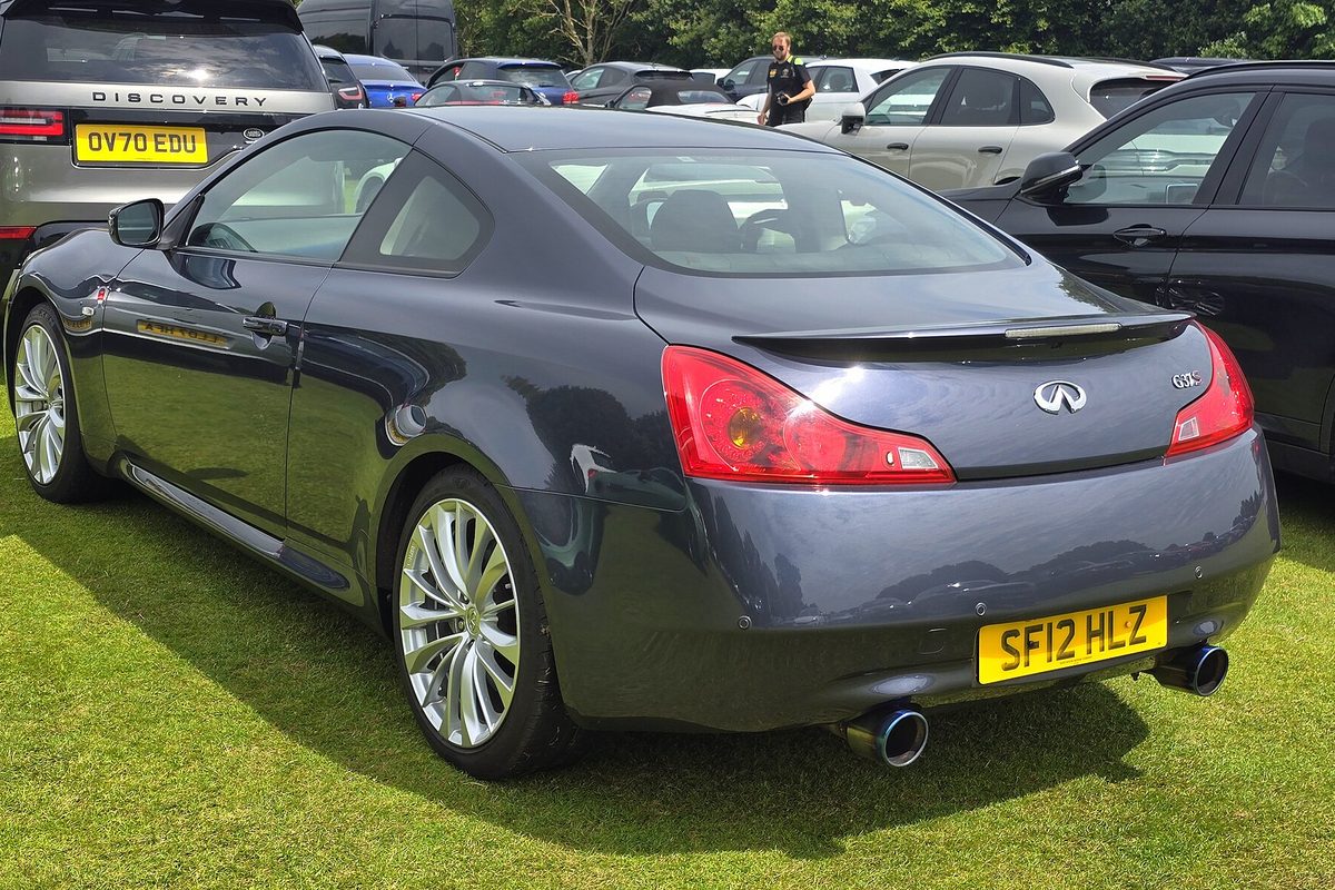 A dark gray Infiniti G37 coupe seen from the rear, parked on grass at a car show