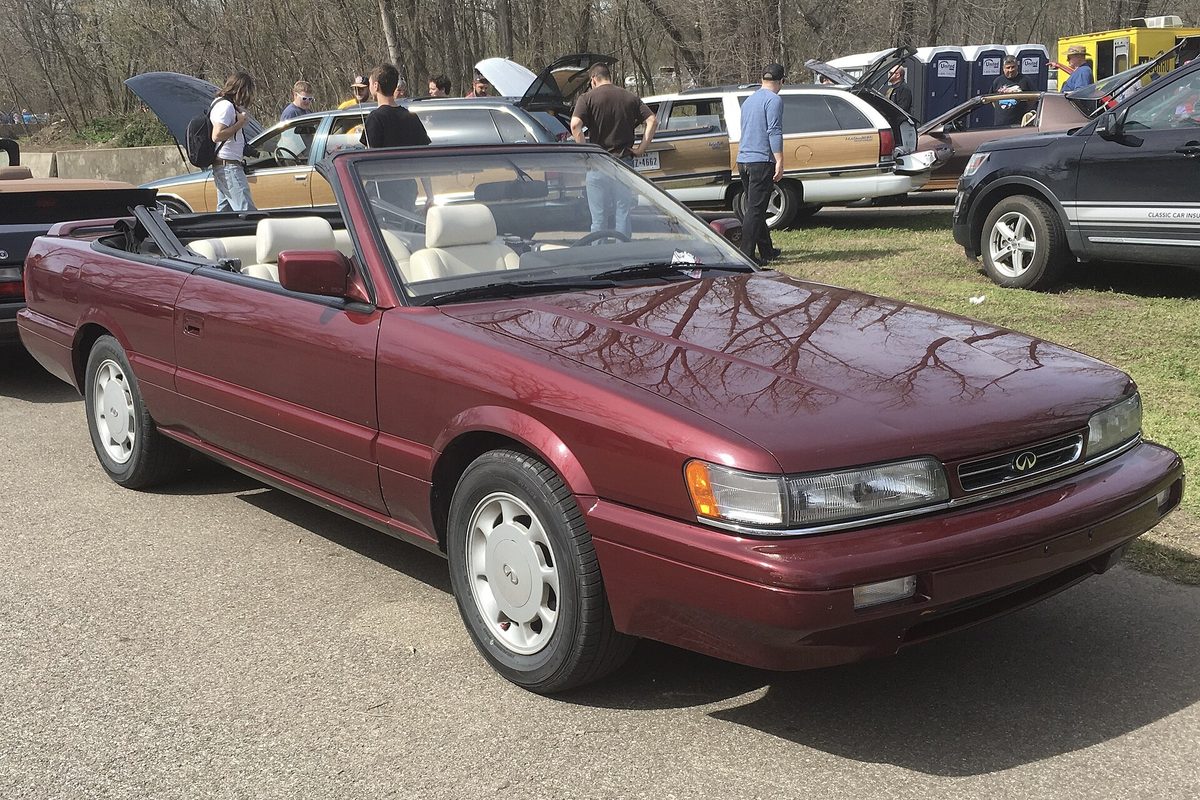 A maroon Infiniti M30 convertible with the top down and tan leather seats, parked at an outdoor car show