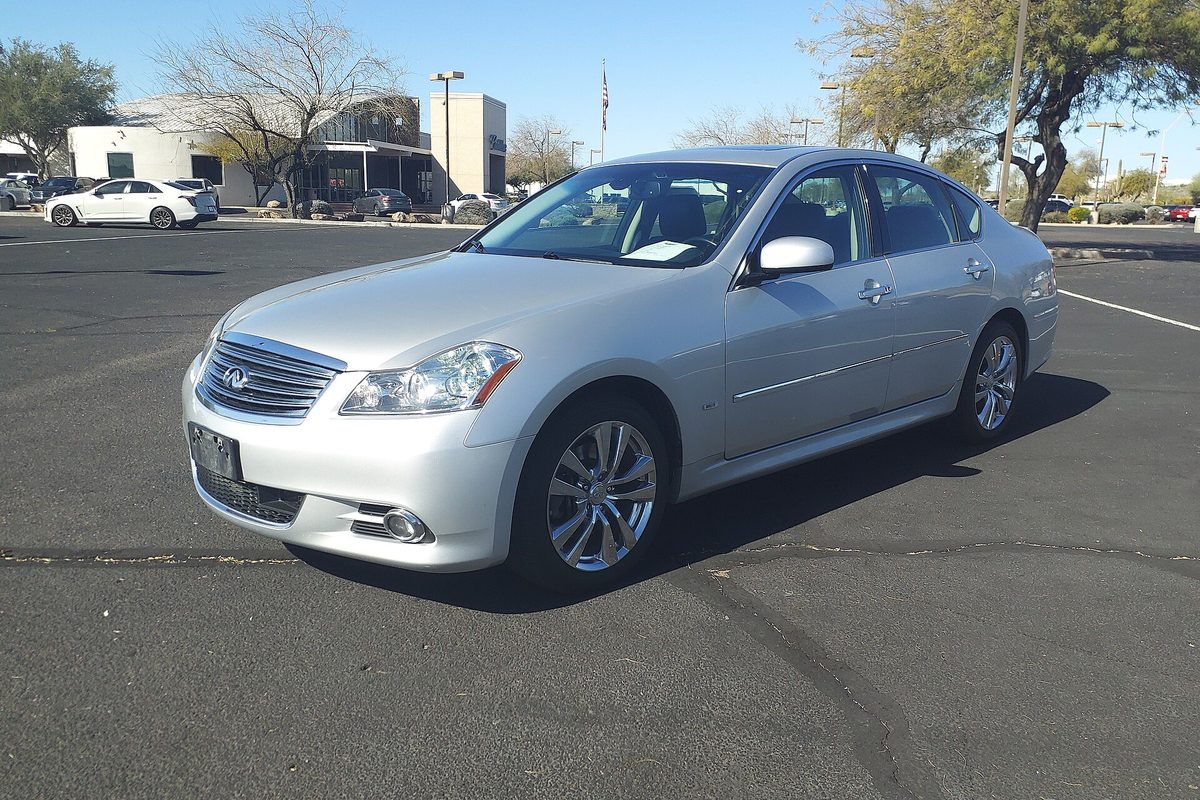 A silver Infiniti M45x sedan parked in a sunny parking lot with trees and a building behind it