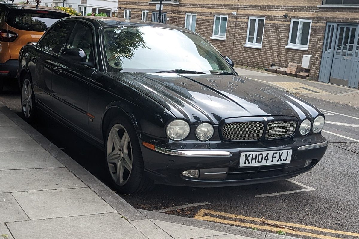 A black Jaguar XJ6 saloon parked at the curb on a town street