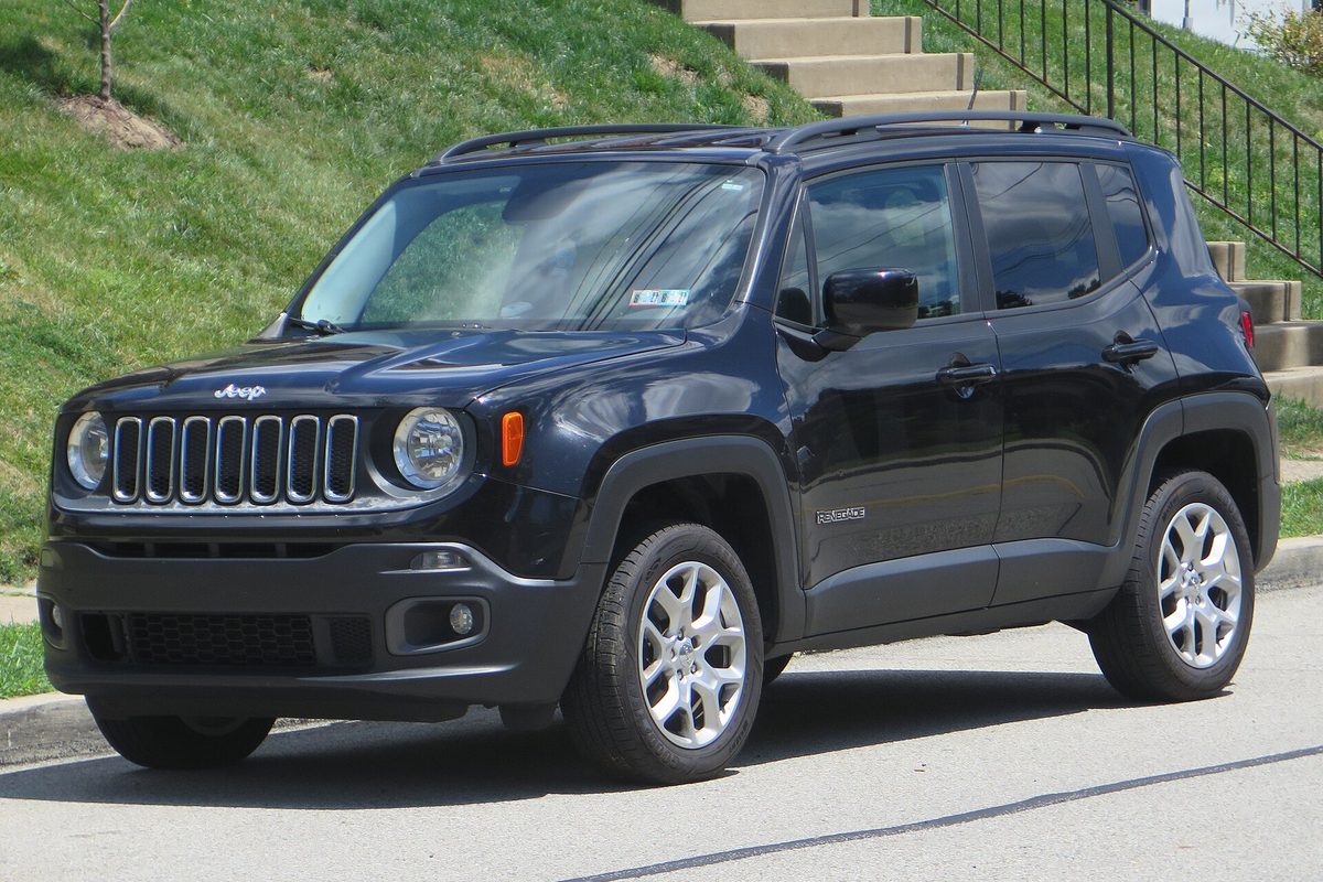 A black 2017 Jeep Renegade Latitude parked on a street below a grassy hill and concrete steps