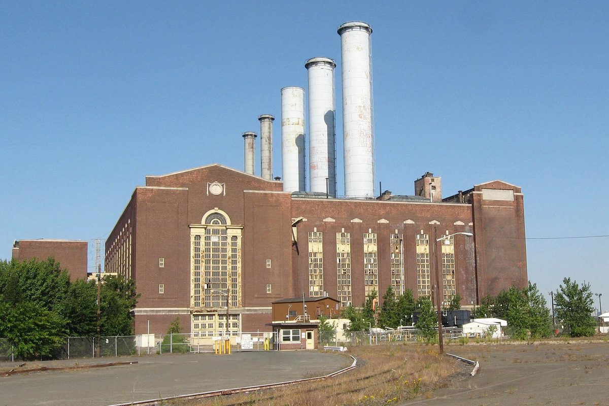 Kearny Generating Station, a brick power plant with tall arched windows and four white smokestacks, under a clear blue sky