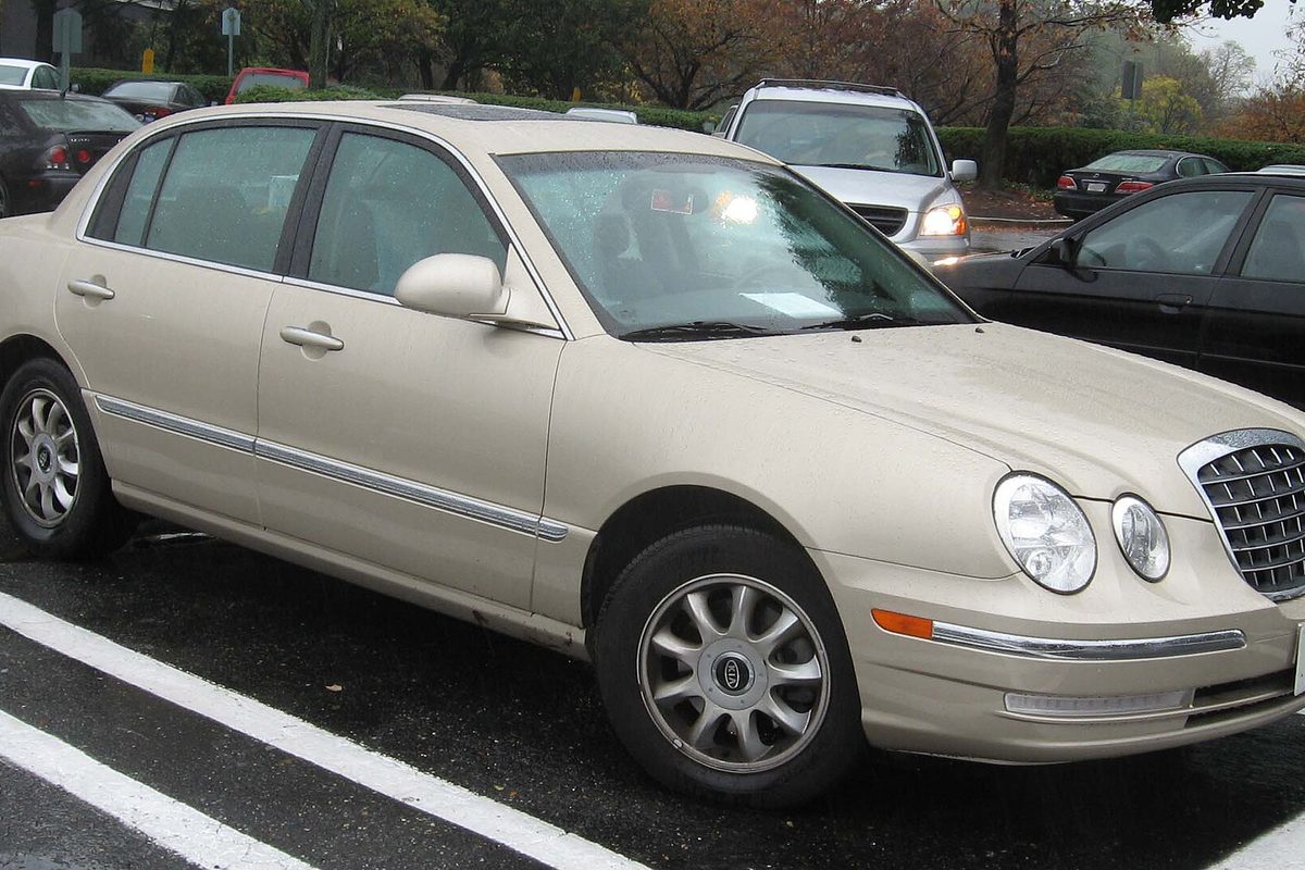 A champagne-colored Kia Amanti sedan parked in a wet parking lot