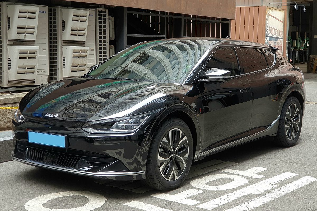 A black Kia EV6 electric crossover parked on a city street over painted road markings, seen from the front corner
