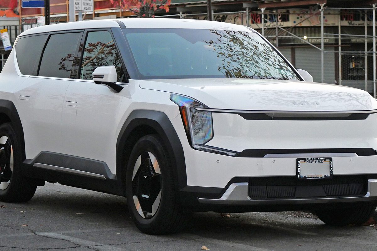 A white Kia EV9 electric SUV parked on a city street, front three-quarter view