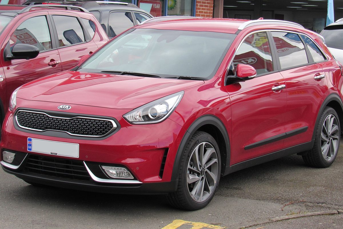 A red Kia Niro crossover, front three-quarter view, parked on a dealership lot