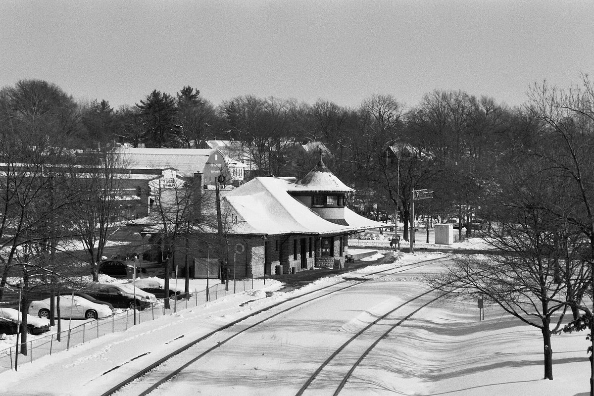 Black and white photo of the Kirkwood train station under snow, seen from the Clay Avenue bridge with the tracks curving past