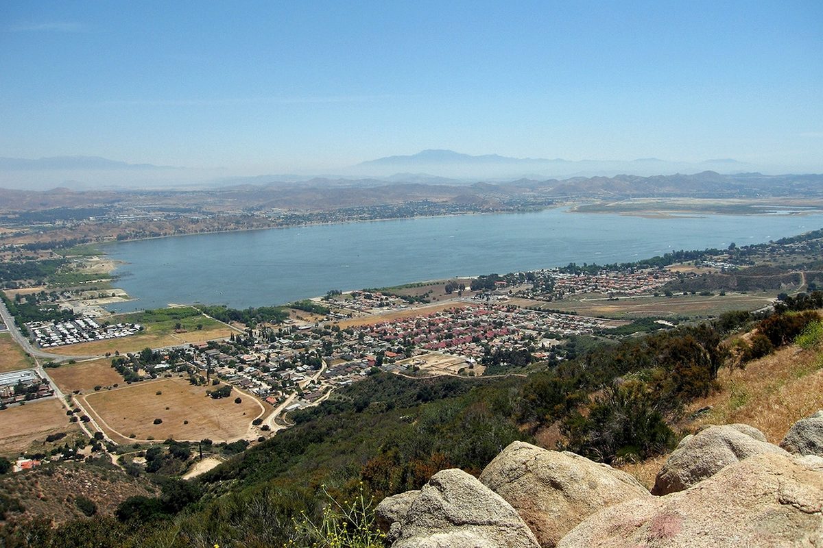 Lake Elsinore and the neighborhoods along its shore seen from the brushy hills off Highway 74, with boulders in the foreground