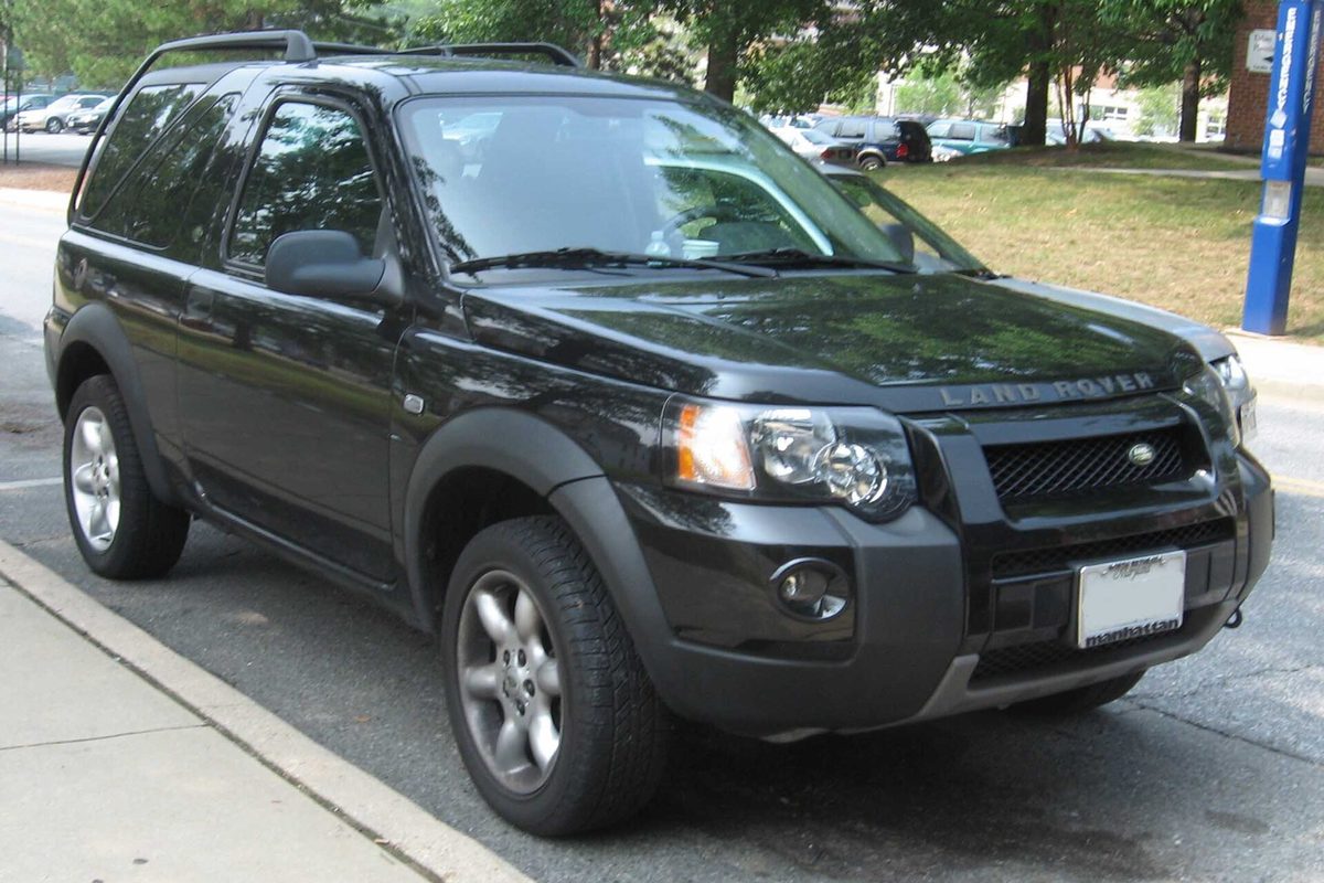 A black three-door Land Rover Freelander parked at a curb on a tree-lined street