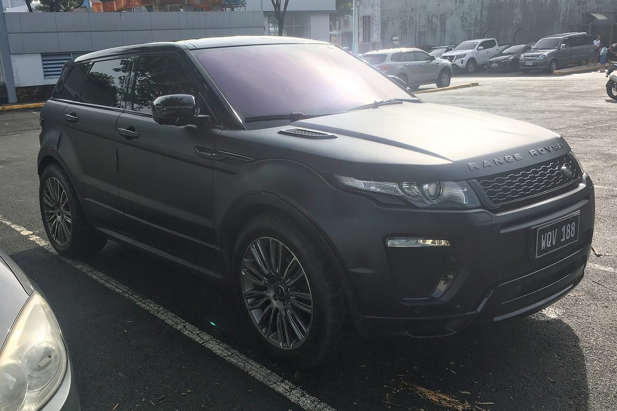 A matte black five-door Range Rover Evoque with dark multi-spoke wheels in a parking lot