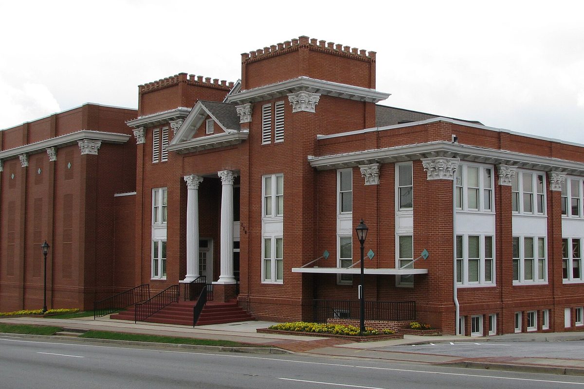 The red brick Aurora Theatre in Lawrenceville, with white columns, ornate capitals and a crenellated roofline, seen from Pike Street on an overcast day