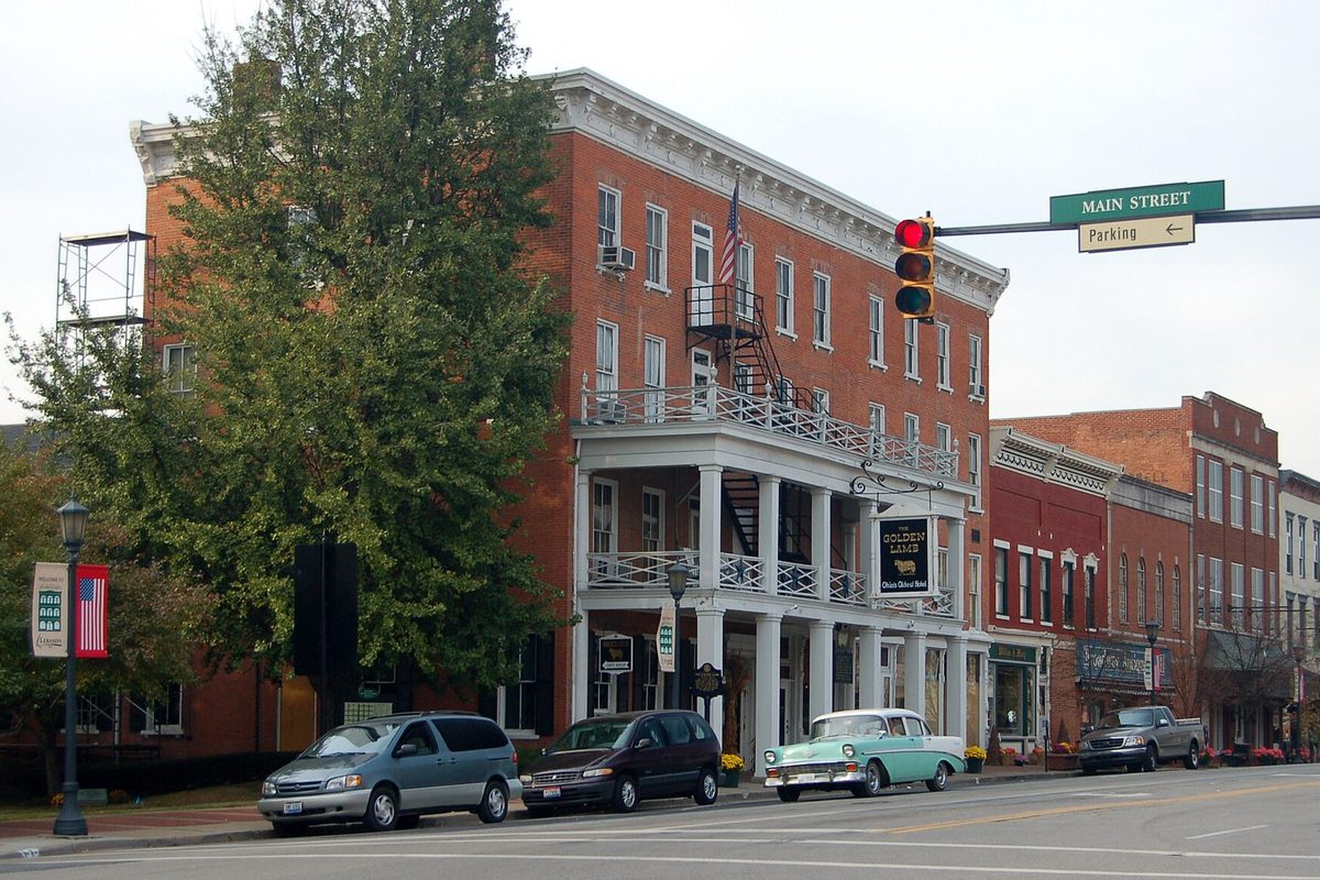 The Golden Lamb, a red brick inn with white two-level porches on Lebanon's Main Street, with a turquoise vintage car parked in front