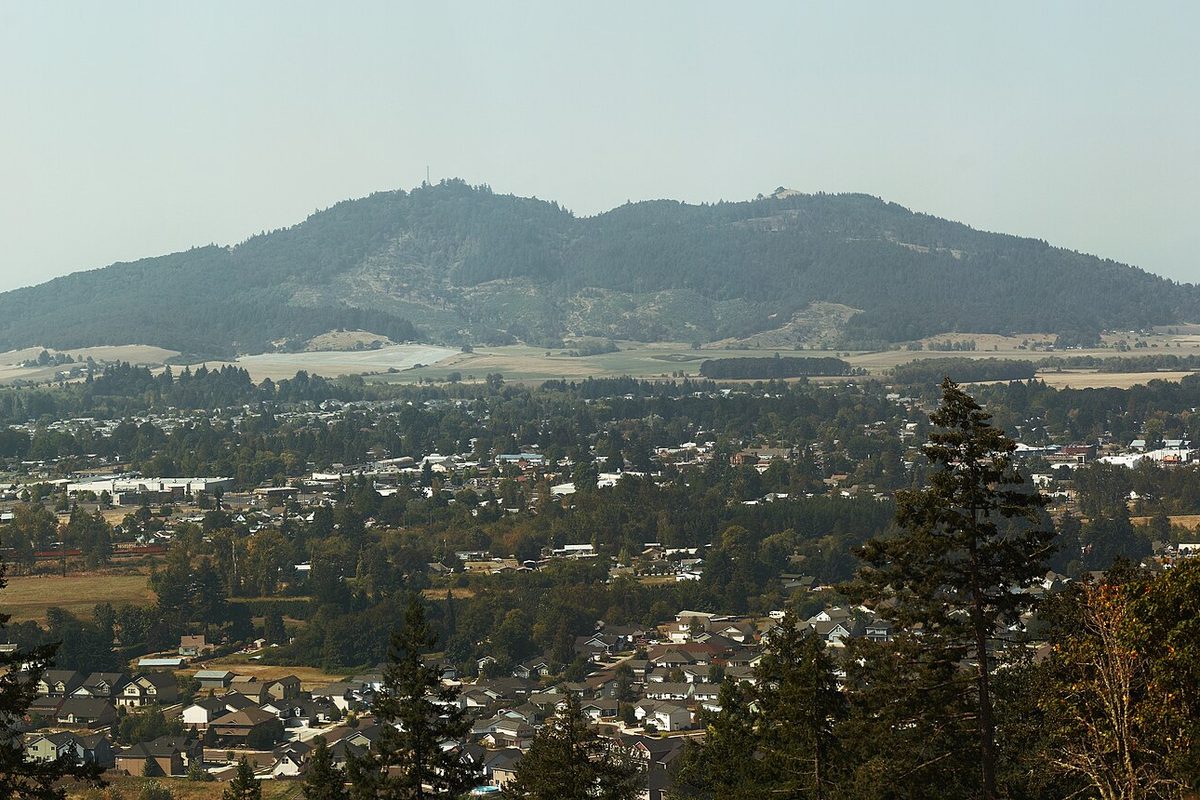 Peterson Butte rising behind the houses and trees of Lebanon, seen from Ridgeway Butte on a hazy day