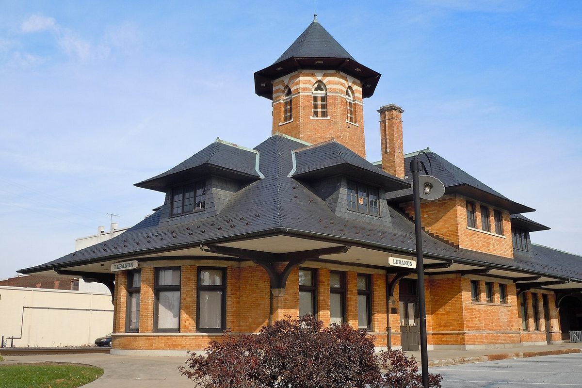 Lebanon's old Reading Railroad station, an orange brick building with dark slate hip roofs and a square central tower with arched windows, under a pale blue sky