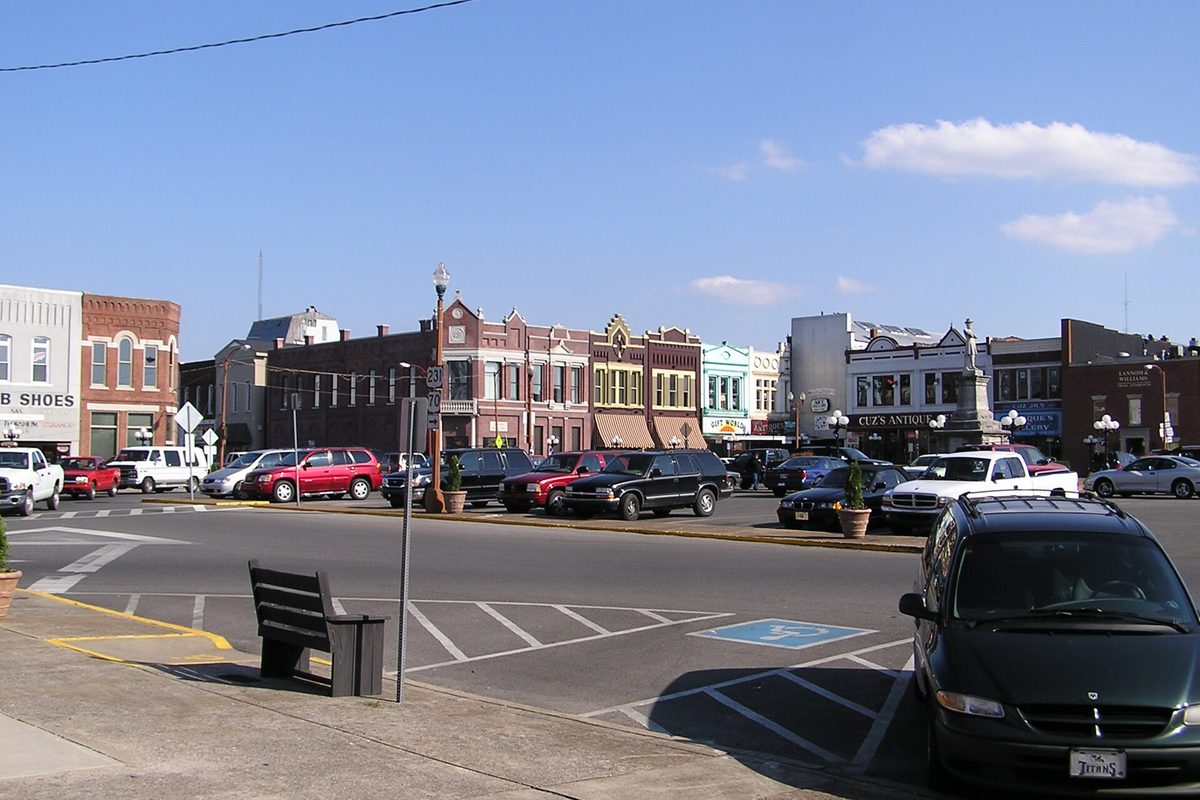 Lebanon's town square on a sunny day, with brick storefronts, parked cars and pickups, and the Civil War memorial statue in the middle