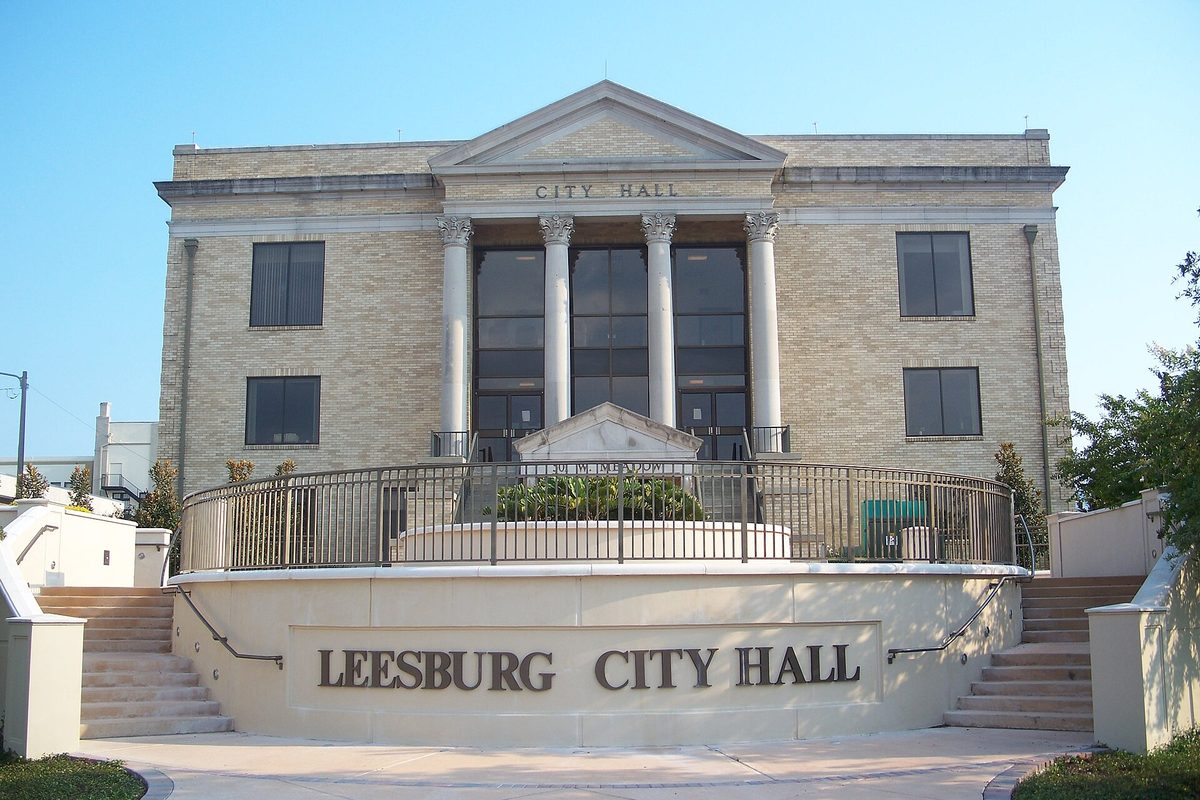 Leesburg City Hall, a tan stone building with tall columns and a pediment, above curved steps and a wall lettered Leesburg City Hall