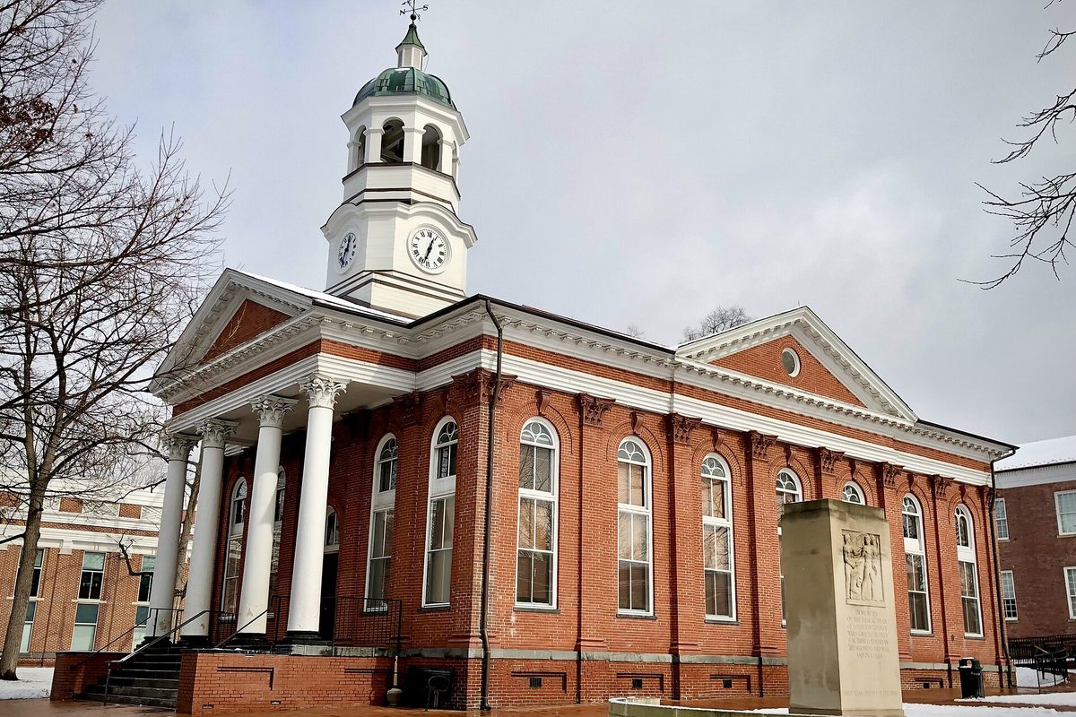 The red brick Loudoun County Courthouse in Leesburg, with white columns, arched windows and a white clock cupola, under a gray winter sky with snow on the ground