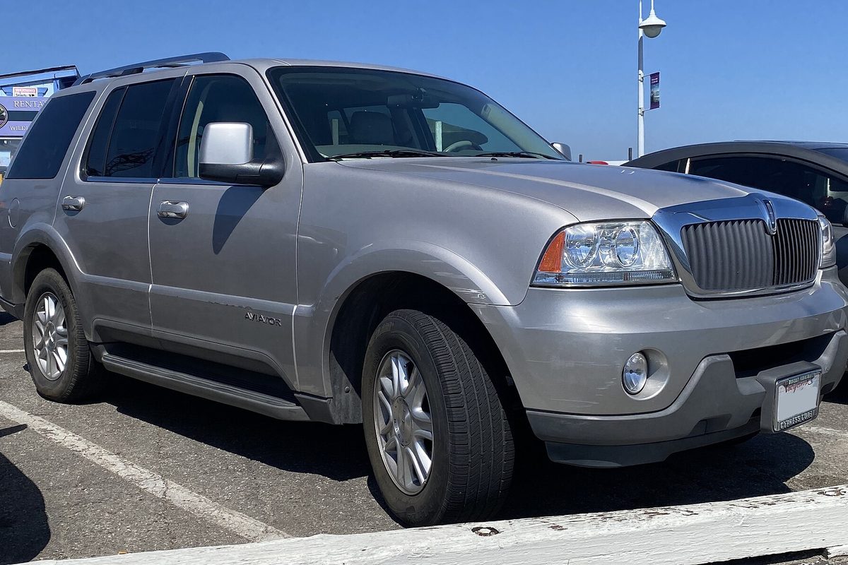 A silver first-generation Lincoln Aviator SUV parked in a lot under a clear blue sky