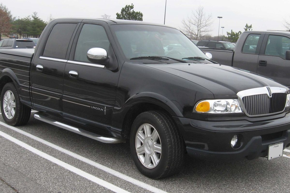 A black Lincoln Blackwood crew-cab pickup with chrome step bars and a chrome grille, parked in a lot