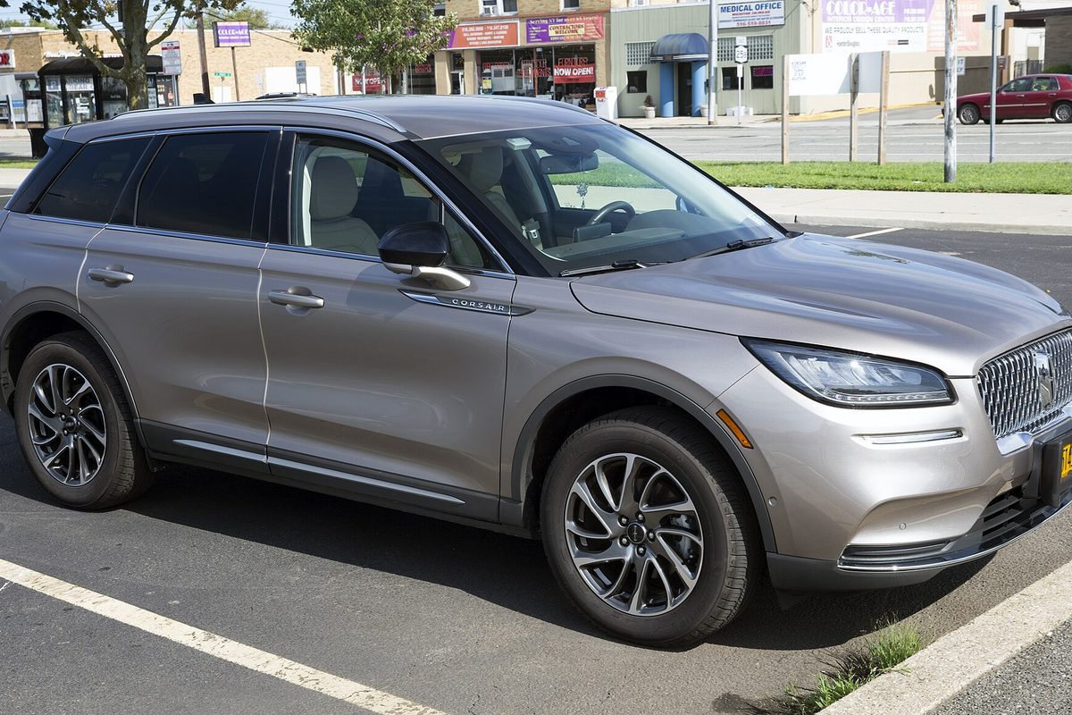 A silver Lincoln Corsair compact SUV parked in a lot in front of a row of small shops
