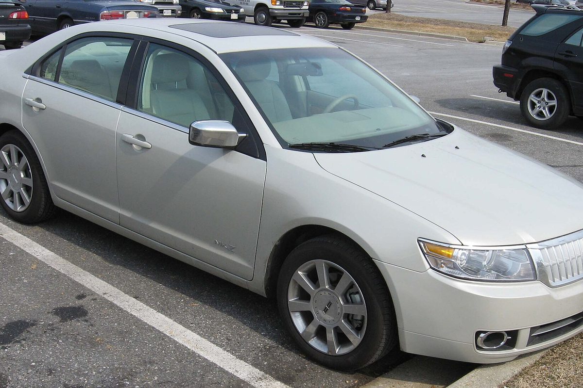 A silver 2007 Lincoln MKZ sedan with a sunroof, parked in a lot beside a black SUV