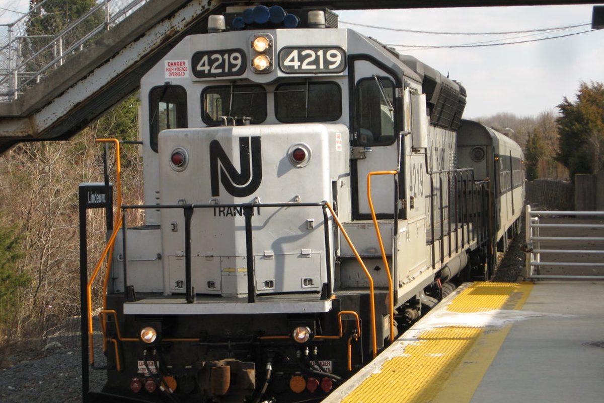 A silver NJ Transit diesel locomotive numbered 4219 pulling into Lindenwold station alongside a platform edged in yellow