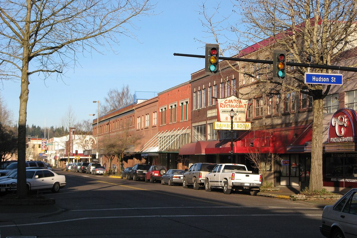 Brick storefronts, a Canton Restaurant sign and parked pickups along Commerce Avenue at Hudson Street in downtown Longview
