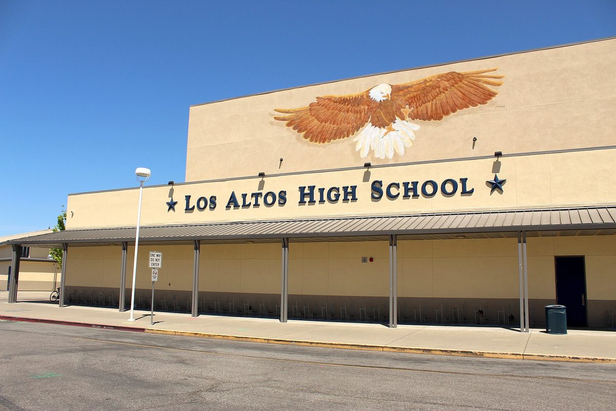 The tan front wall of Los Altos High School, with a large painted eagle above the school's name and a covered walkway below