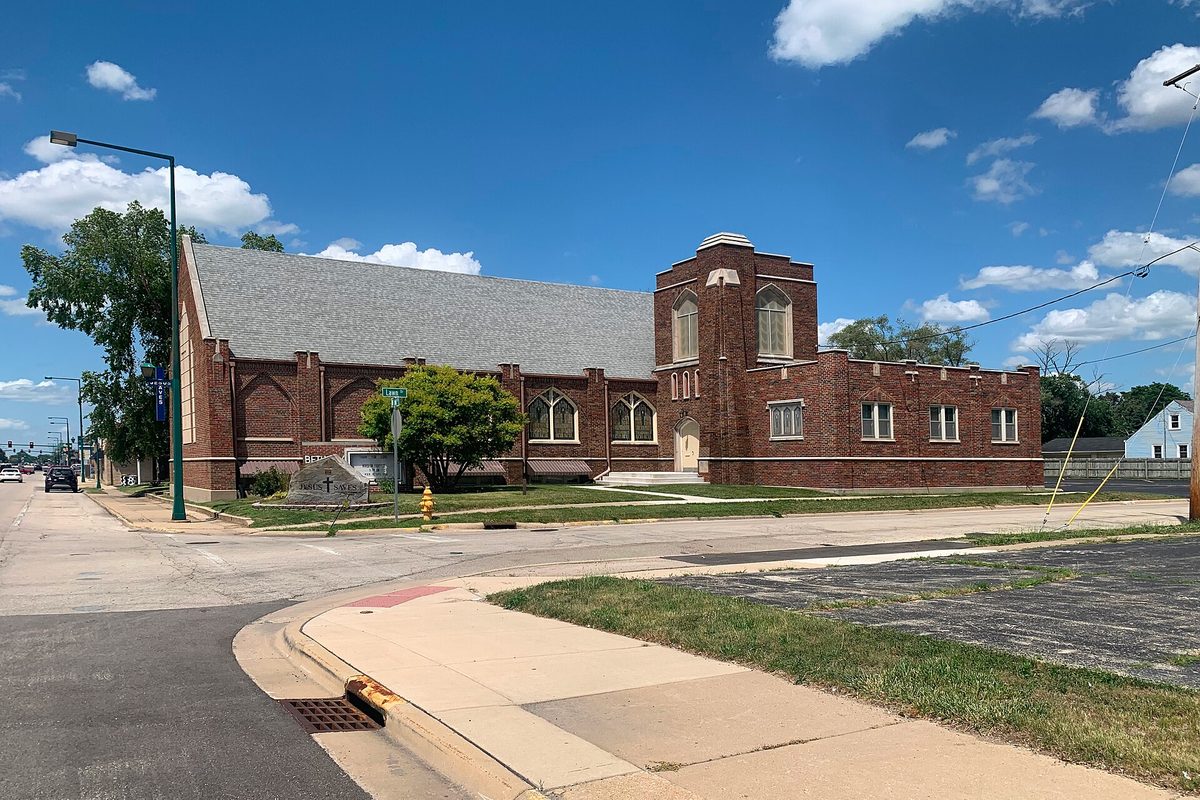 Bethany Presbyterian Church in Loves Park, a red brick church with a square tower and arched windows on a street corner under a blue sky