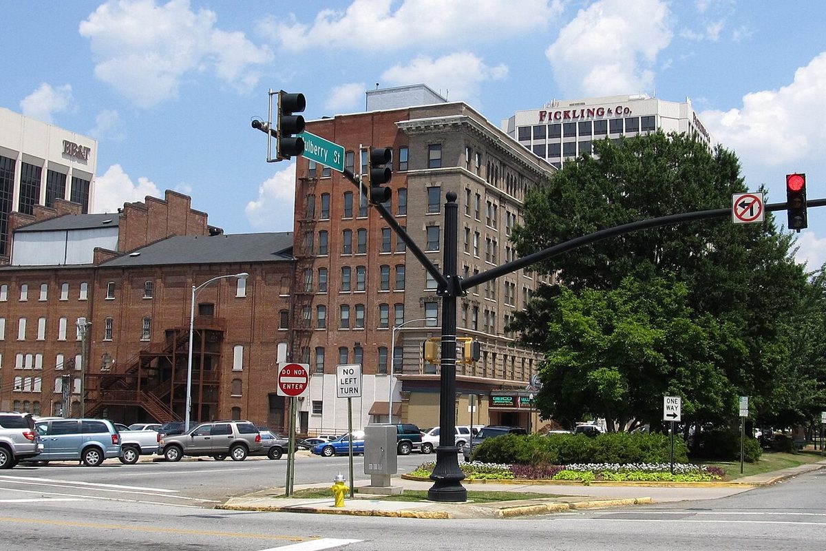 A traffic signal and a Mulberry Street sign at a downtown Macon intersection, with old brick and stone office buildings and parked cars behind