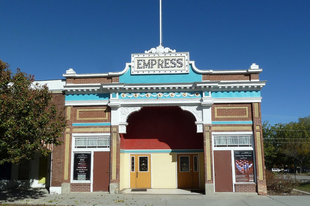 The Empress Theatre on Magna's Main Street, a brick front with turquoise trim, a white EMPRESS sign and an arched entrance under a blue sky