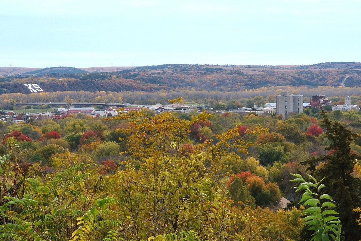 Autumn trees in gold and red over downtown Manhattan, Kansas, with the white KS letters on K-Hill across the valley