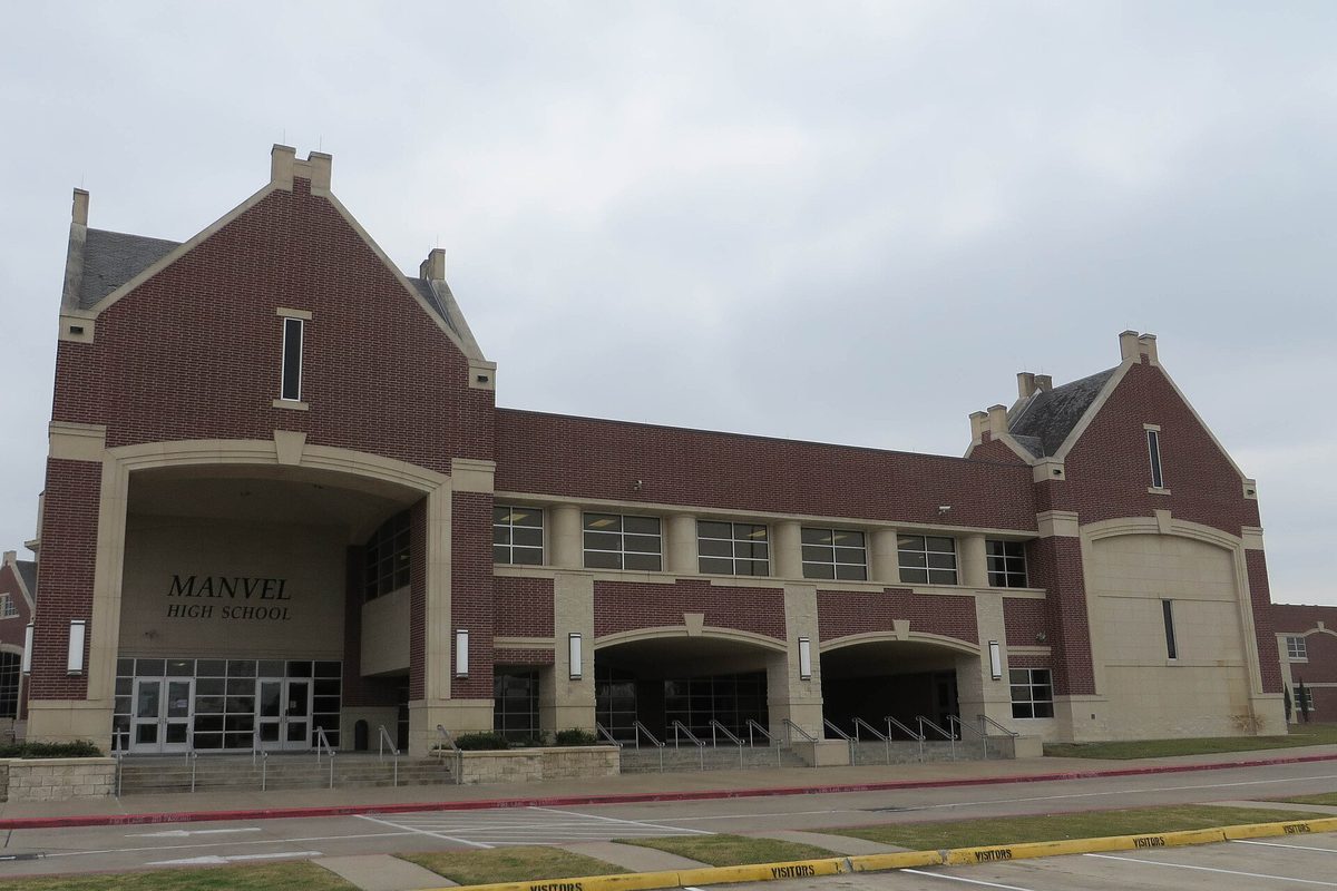 Manvel High School, a red brick building with stone trim, steep gables and the school's name over a deep entry arch, under a gray sky