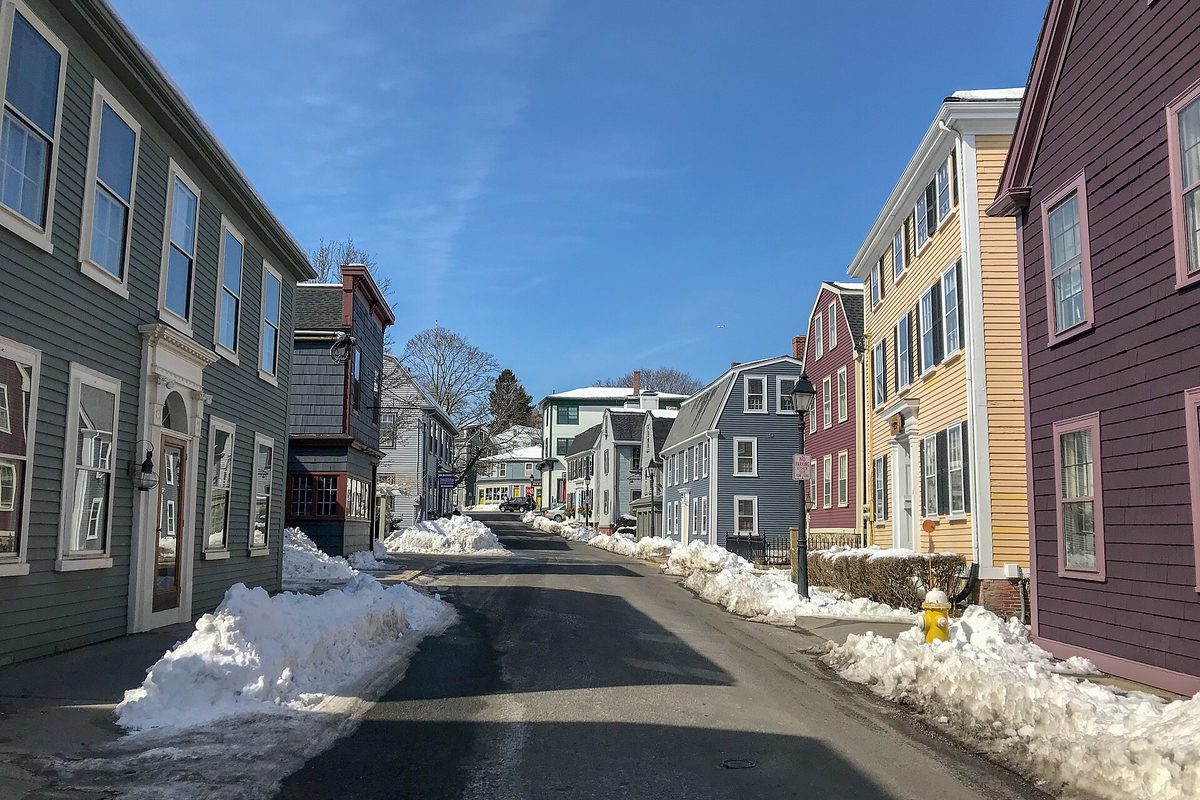 Colorful clapboard houses line State Street in Marblehead, with snowbanks along both curbs under a clear blue sky