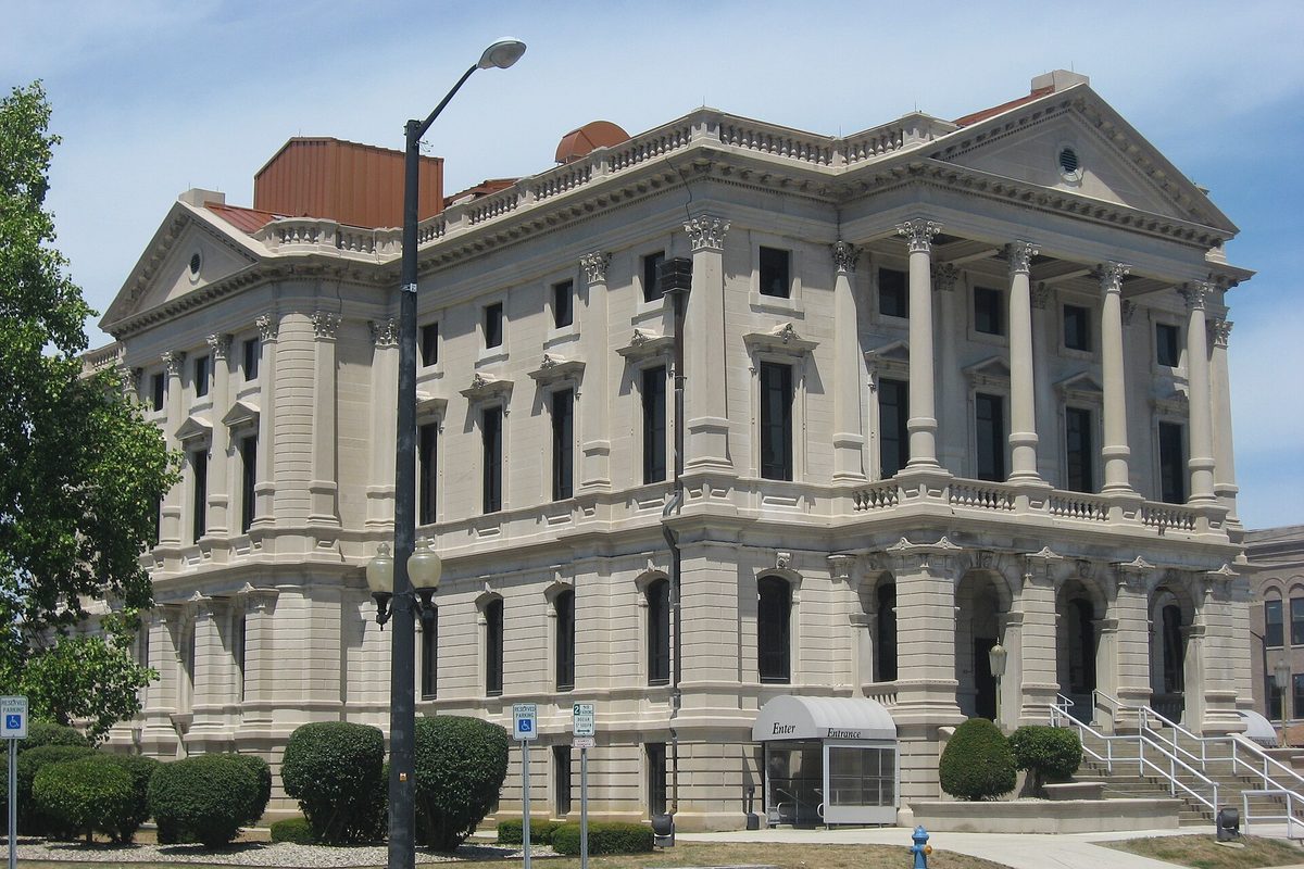 The pale stone Grant County Courthouse in downtown Marion, with tall columns, a carved pediment and a street lamp in front