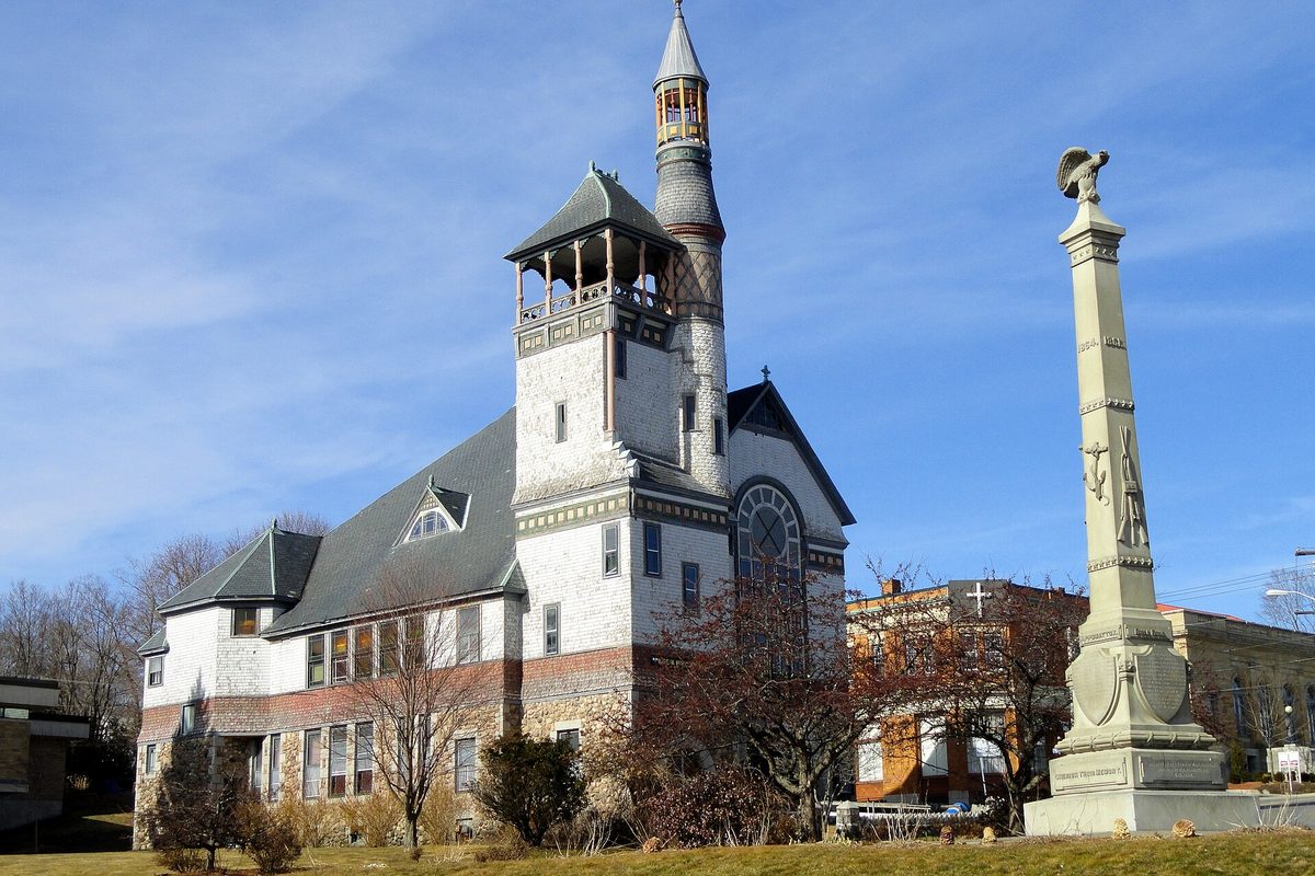 Monument Square in Marlborough: a white church with a turreted tower and a tall stone Civil War soldiers' monument, under a blue sky