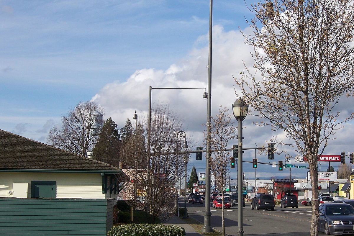 State Avenue in downtown Marysville looking north, with traffic signals, street lamps, bare trees and the city water tower behind the evergreens
