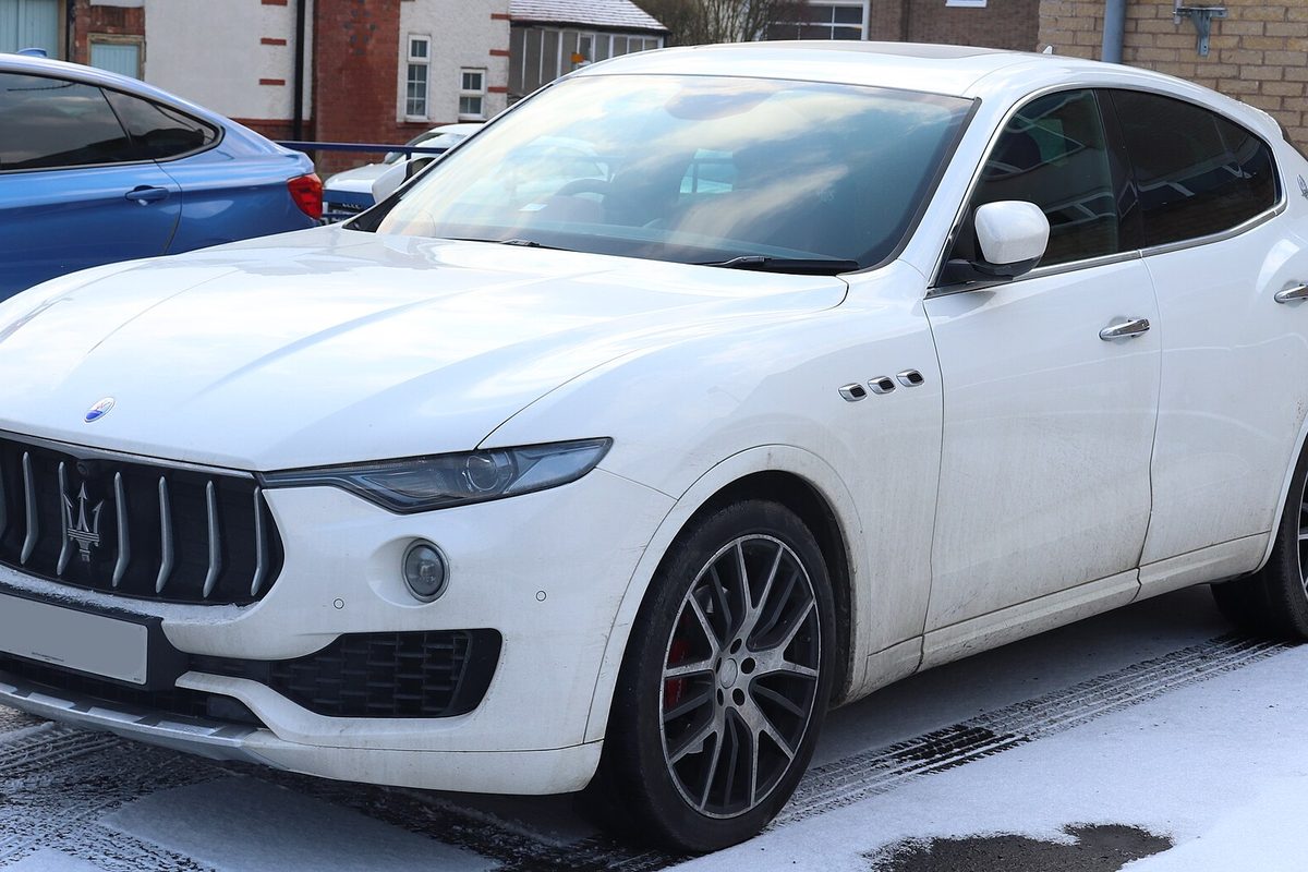 A white Maserati Levante SUV parked on a snow-dusted lot in front of a brick building