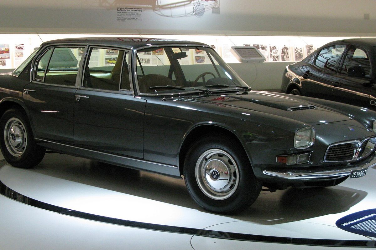 A dark gray Maserati Quattroporte, the first generation of the four-door sedan, displayed on a round museum platform