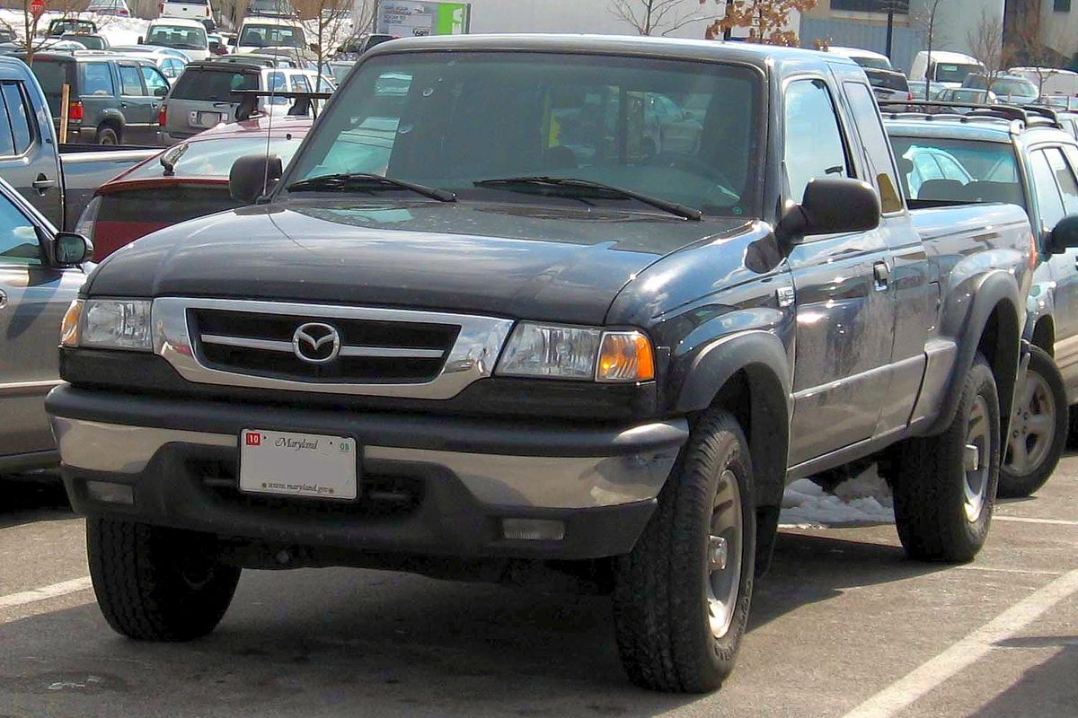 A dark gray Mazda B-Series extended-cab pickup parked in a lot with patches of snow, seen from the front