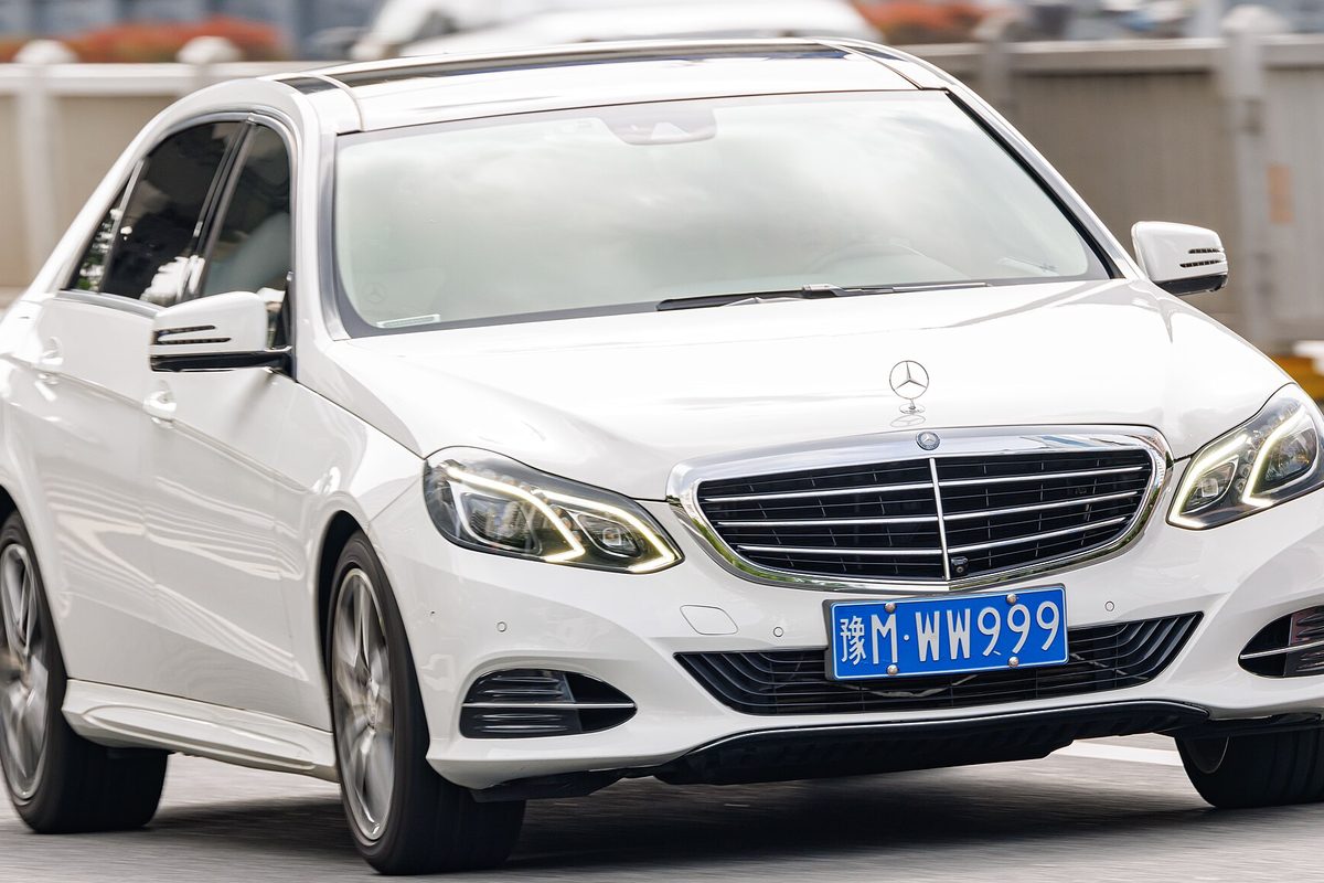 A white W212 Mercedes-Benz E-Class long-wheelbase sedan with LED headlights, seen from the front on a city street