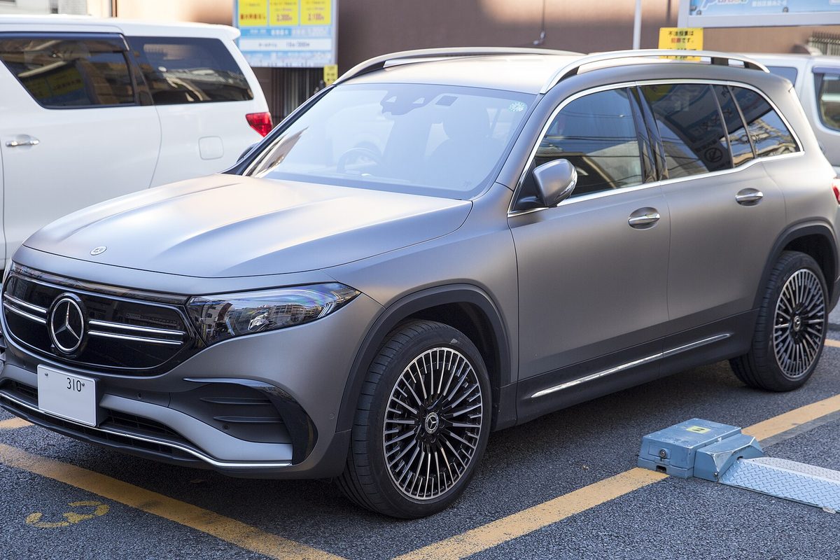 A matte gray Mercedes-Benz EQB electric SUV with multi-spoke wheels parked in a marked parking space
