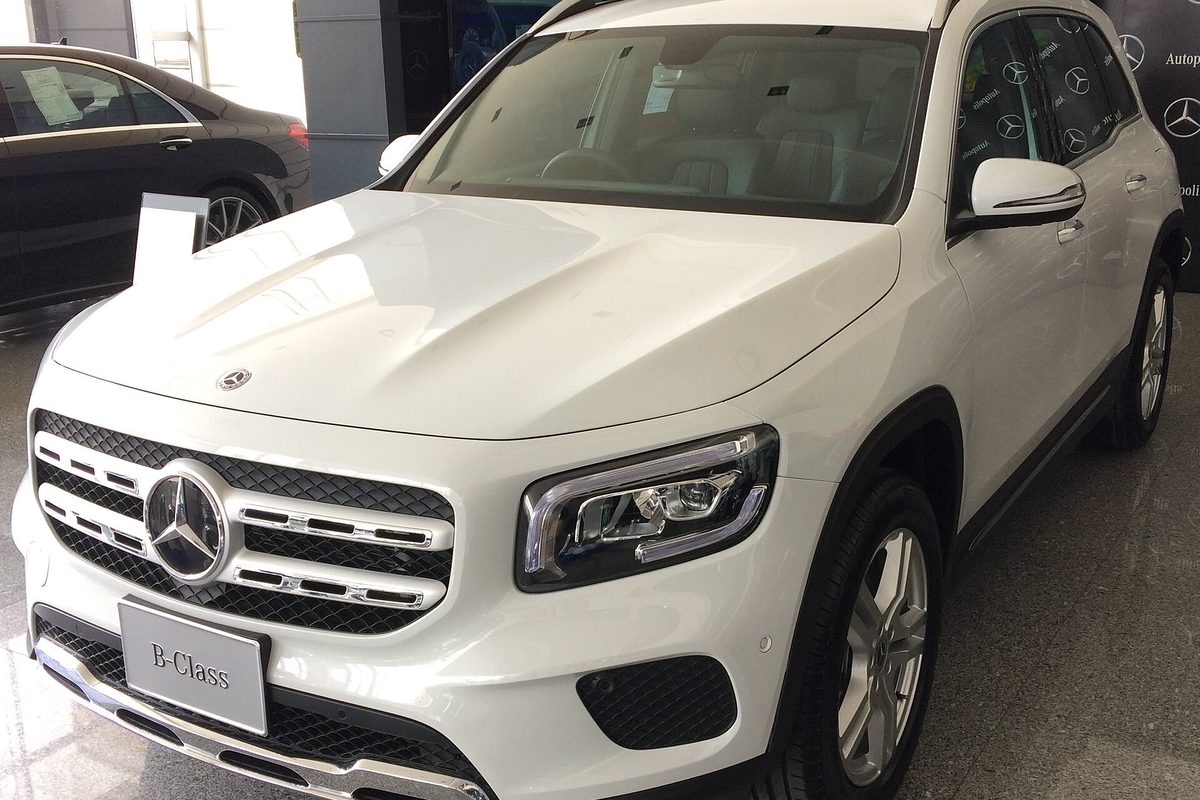 A white Mercedes-Benz GLB-Class SUV on a dealership showroom floor, seen from the front