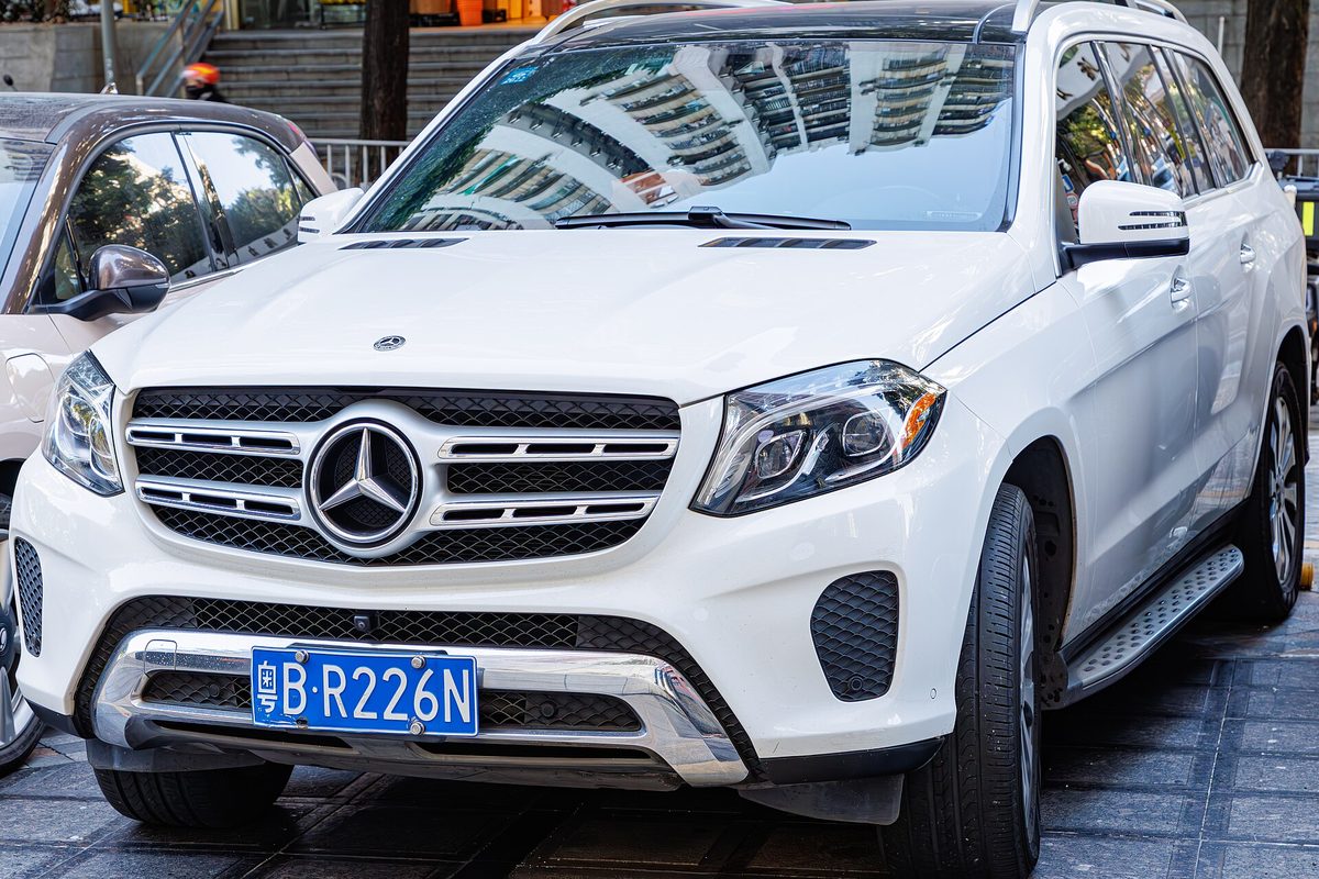 A white Mercedes-Benz GLS-Class SUV (X166 body) seen from the front, parked on a city sidewalk